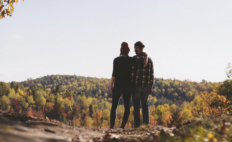 Kirándulók az őszi erdőt nézik a dombról.