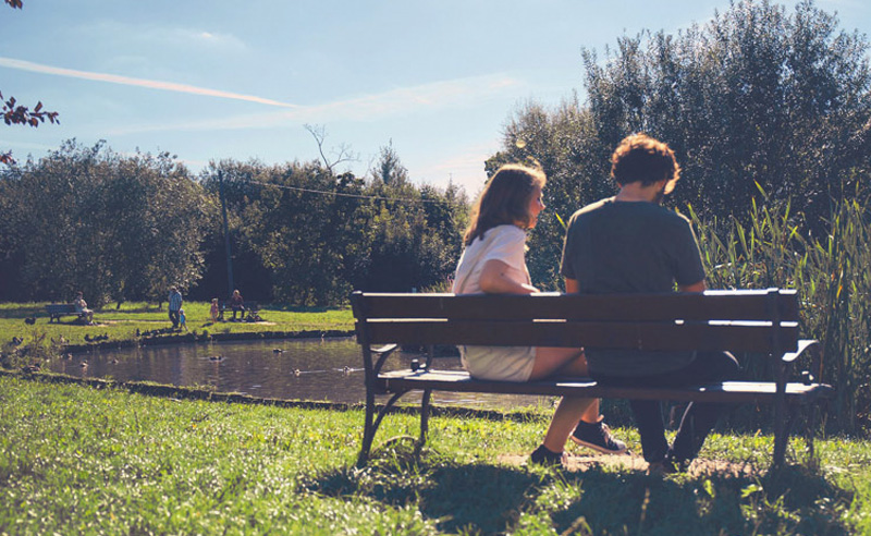 Férfi és nő padon ülve, a tó mellett.