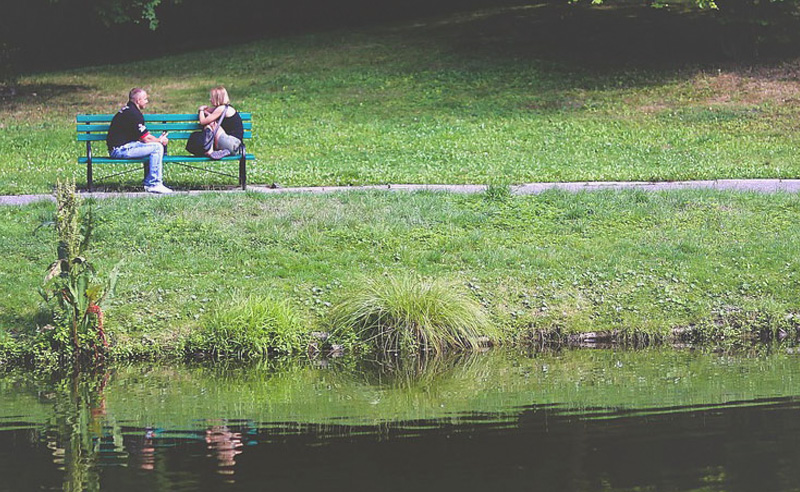 Férfi és nő tóparti padon beszélgetnek