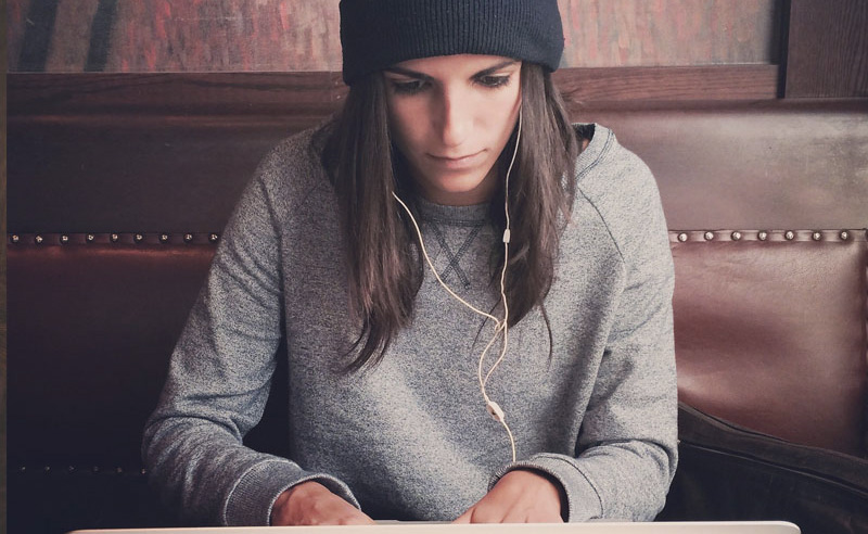 Lány fülhallgatóval bőrszéken laptoppal