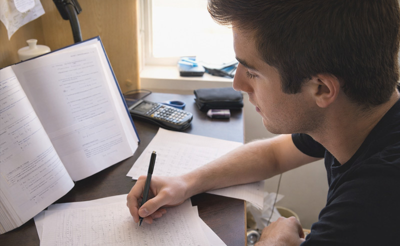 Fiú asztalnál könyvvel tanul